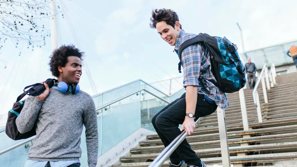 Young man sliding down a stair railing with friend
