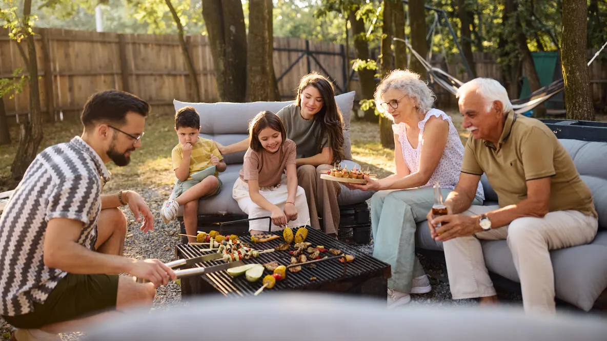 A family cooking on a firepit grill in the backyard