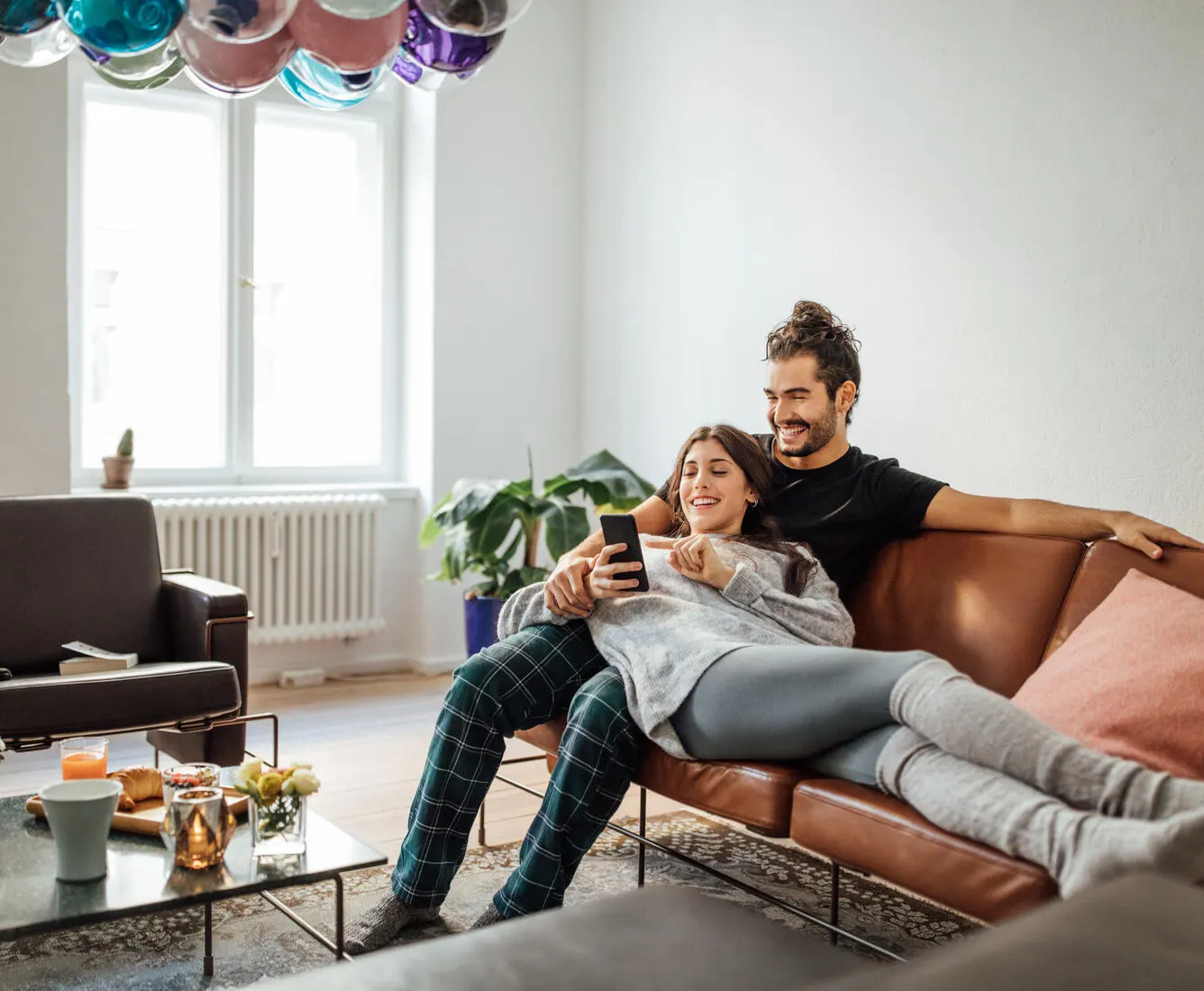 Man and women sitting on couch, browsing on a smartphone