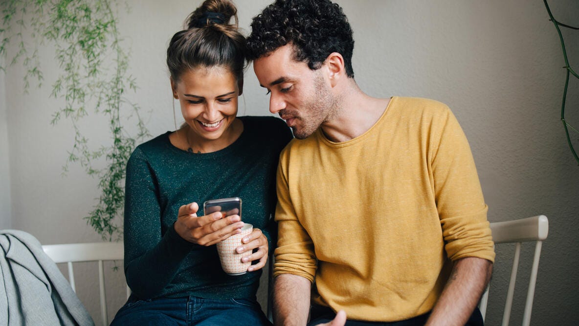 A couple having coffee, looking at a smart phone.