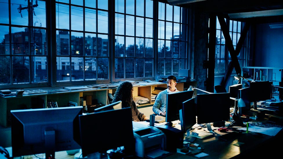 Two business partners working into the night with one desk lamp.
